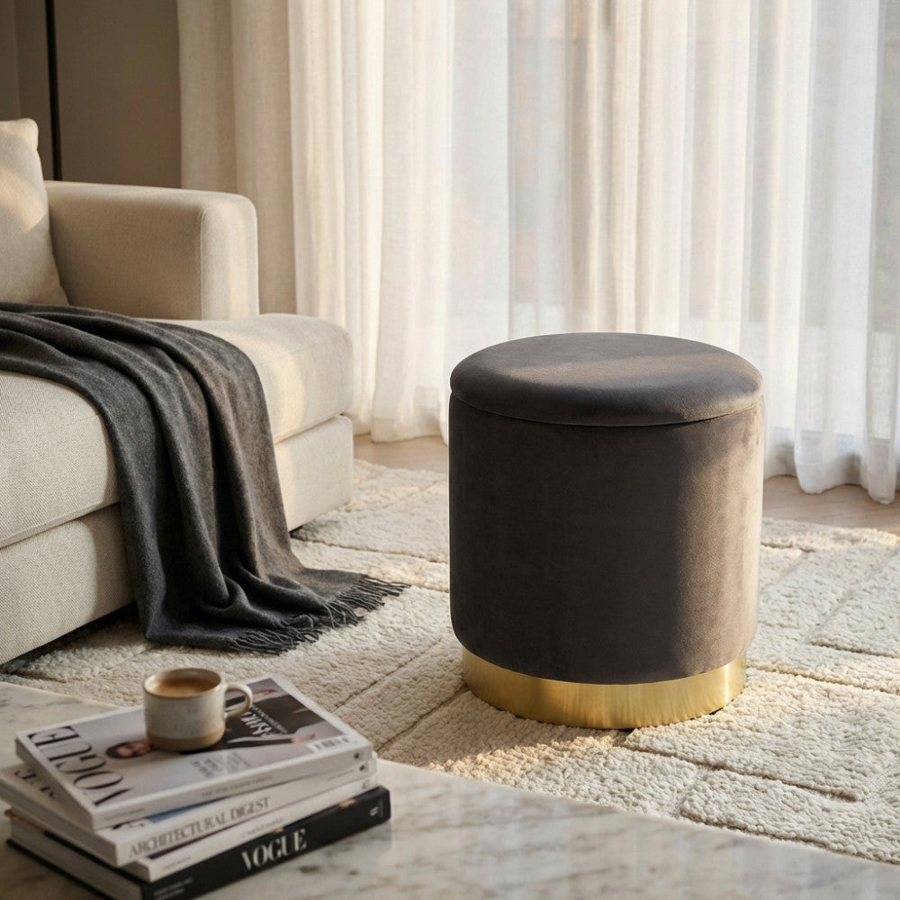 Dettaglio del pouf in velluto grigio scuro posizionato su un tappeto materico, evidenziando il contrasto con il tavolino in marmo.