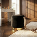 Pouf contenitore rotondo in velluto nero con base dorata, ambientato in una camera da letto lussuosa con pavimento in parquet.