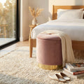 Pouf contenitore in velluto rosa posizionato in una luminosa camera da letto moderna.