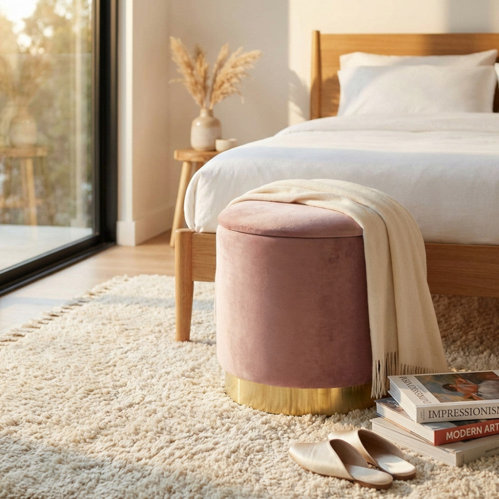 Pouf contenitore in velluto rosa posizionato in una luminosa camera da letto moderna.