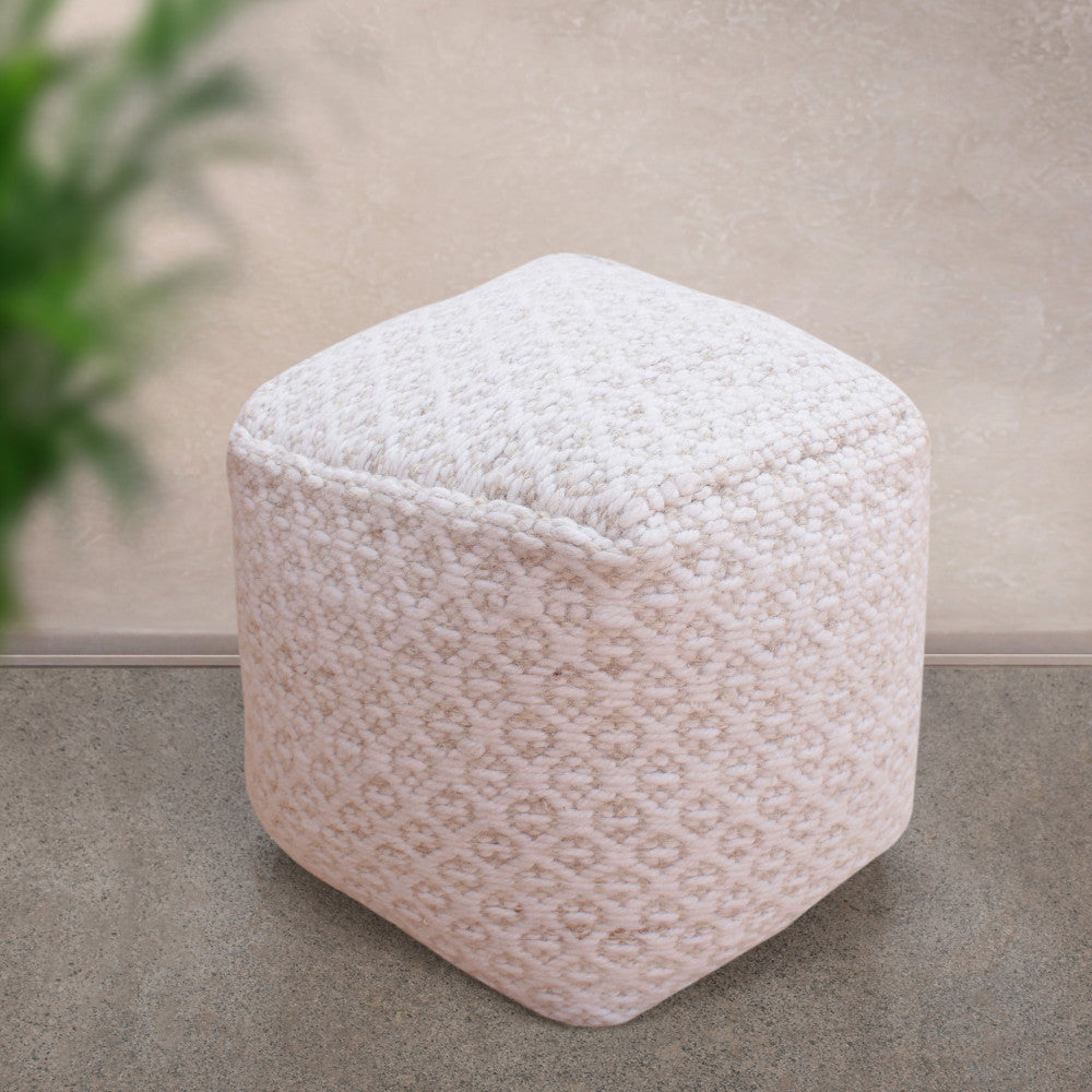 Pouf Jean in un ambiente minimalista con pavimento in pietra e dettagli botanici sfocati sullo sfondo.