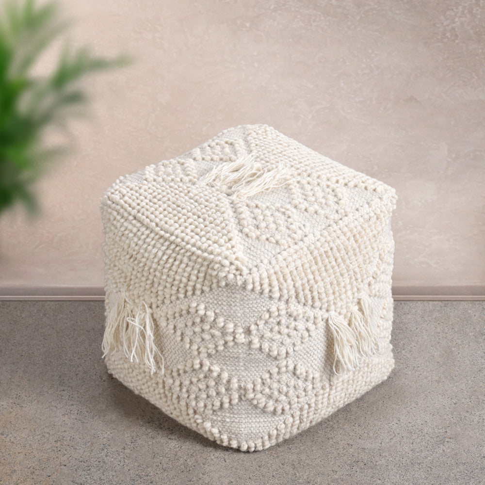 Pouf Jildaz in lana e cotone bianco inserito in uno spazio minimalista con pavimentazione in pietra e dettagli naturali.