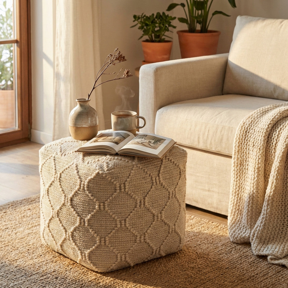 Dettaglio del Pouf Méliton utilizzato come tavolino con un libro aperto e una tazza, illuminato dalla luce naturale.