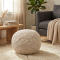 Pouf Midar in cotone bianco con lavorazione macramè, posizionato su un tappeto materico in un salotto boho chic.