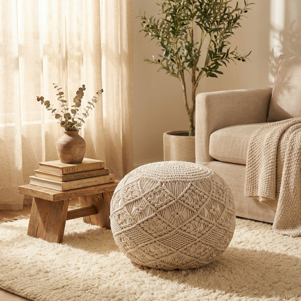 Dettaglio del pouf Midar in cotone intrecciato accanto a un tavolino in legno rustico e un divano neutro.