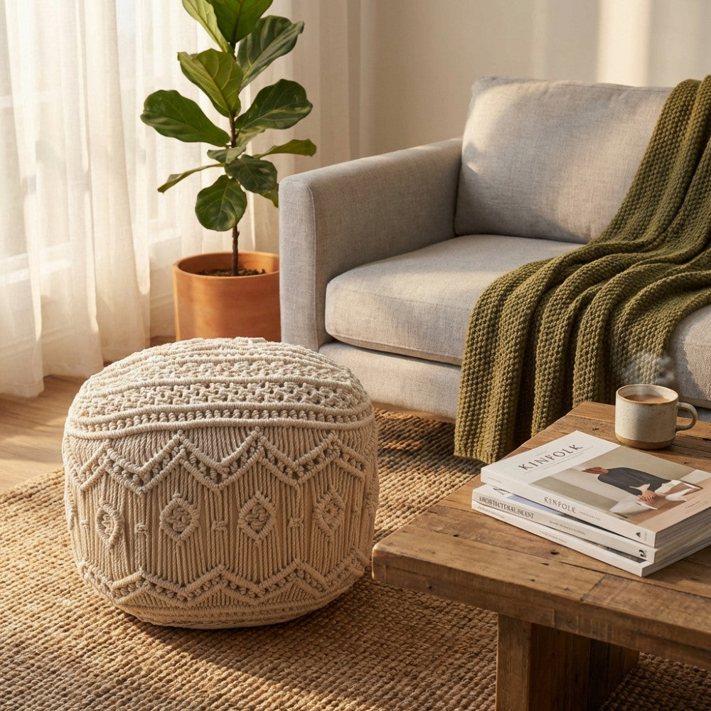 Pouf MILAS in cotone bianco con lavorazione macramè, ambientato in un accogliente soggiorno boho chic accanto a un divano grigio e un tavolino in legno.