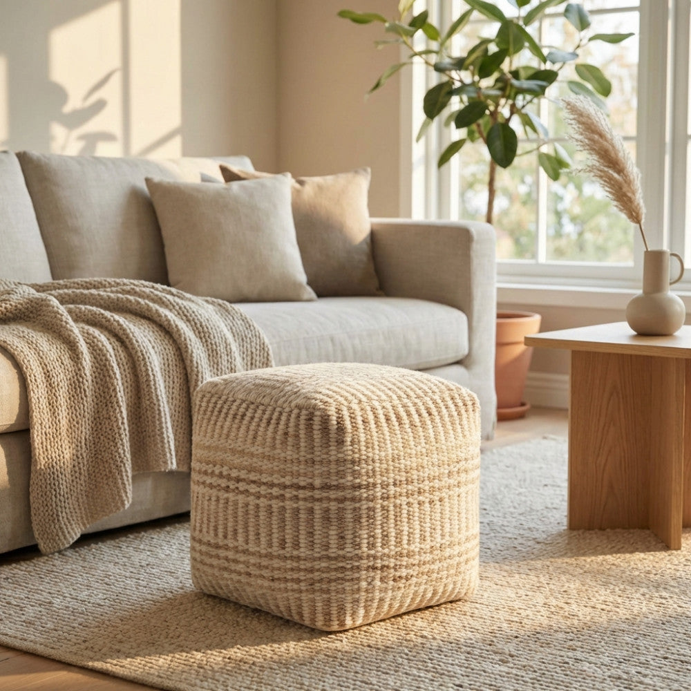 Pouf Roméo in lana e cotone bianco ecrù, posizionato su un tappeto testurizzato in un luminoso soggiorno dal design moderno.