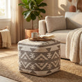 Pouf Romaric in lana e cotone taupe e bianco, utilizzato come tavolino con vassoio e tazza in un luminoso salotto moderno.