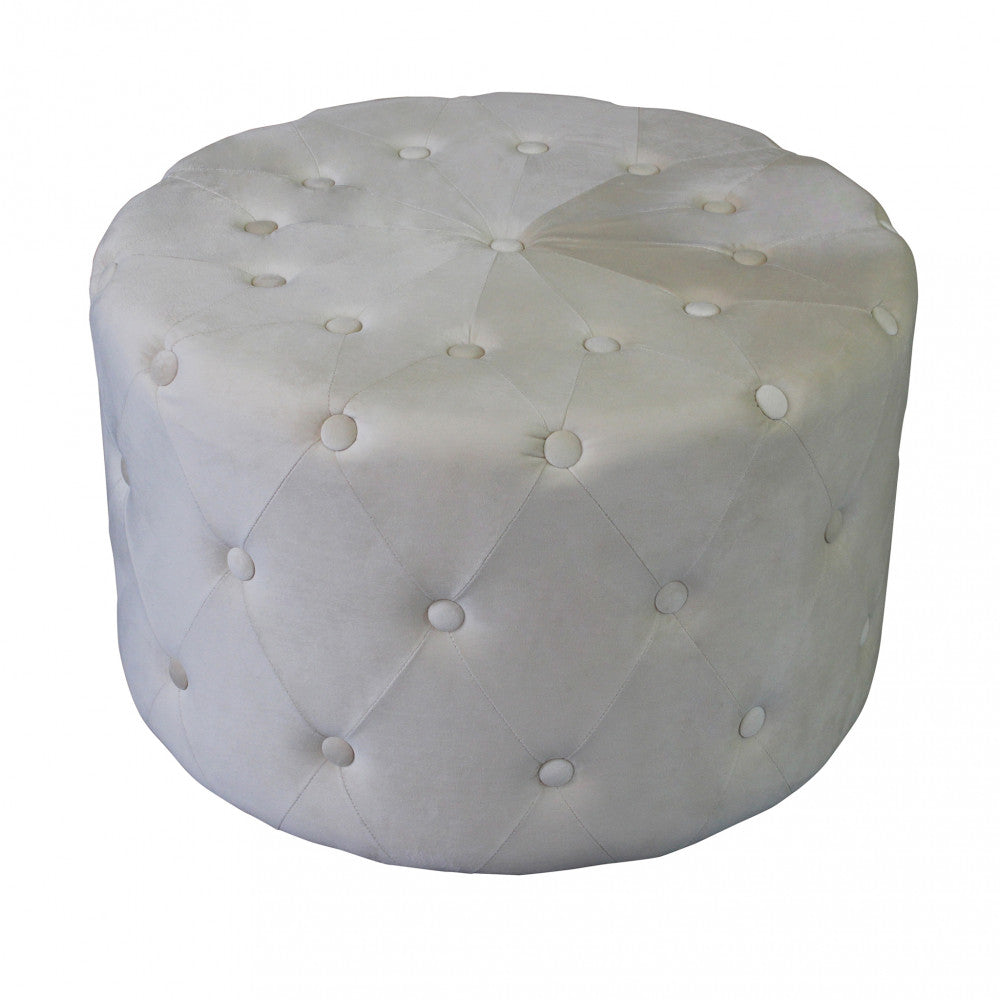 Vista angolata del pouf rotondo in velluto beige che mostra i dettagli dei bottoni rivestiti.