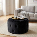 Pouf rotondo in velluto nero con lavorazione capitonné, utilizzato come tavolino da salotto con vassoio dorato.