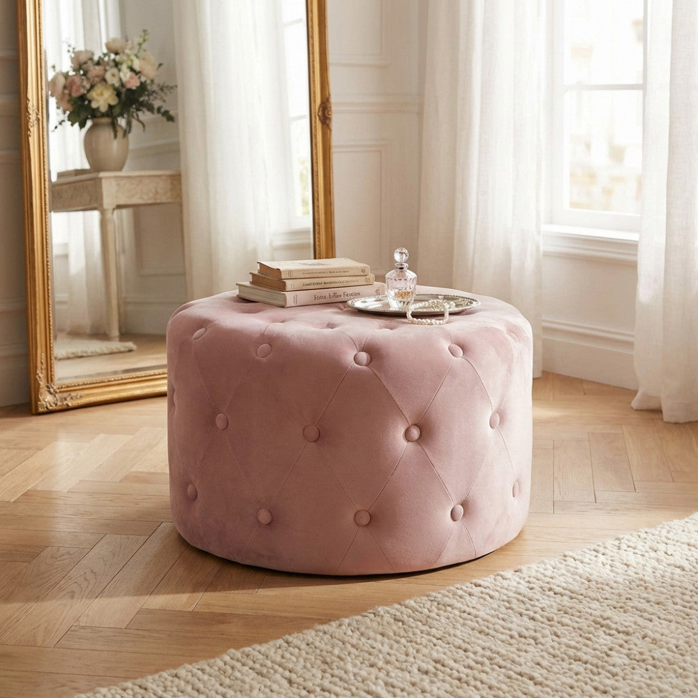 Pouf in velluto rosa allestito come tavolino centrale con libri d'arte e un vassoio in argento in un ambiente luminoso.