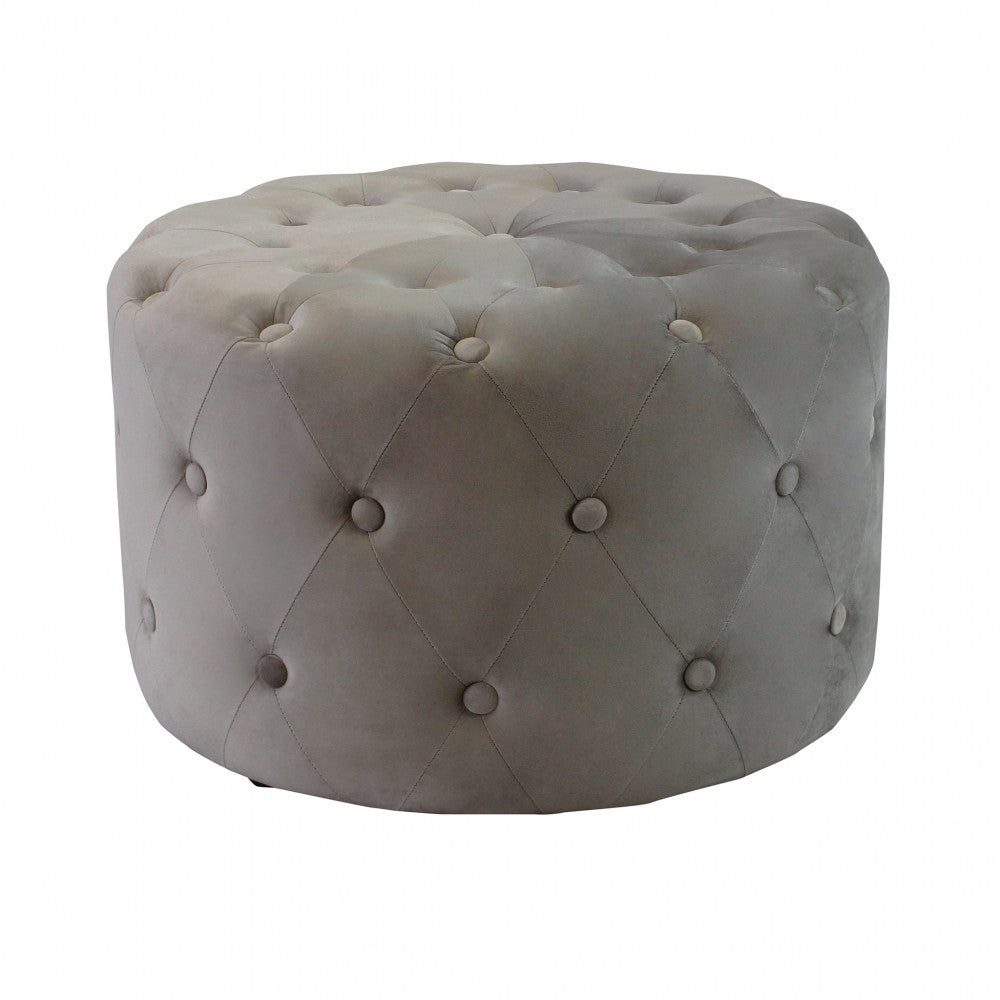 Scatto in studio del pouf rotondo in velluto tortora con profonda lavorazione capitonné, isolato su sfondo bianco.