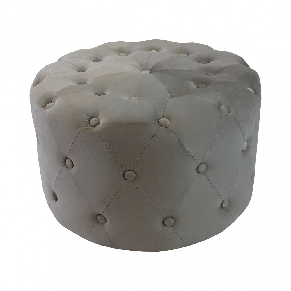 Inquadratura dall'alto in studio del pouf rotondo in velluto tortora capitonné, che mostra i dettagli dei bottoni superiori, isolato su sfondo bianco.