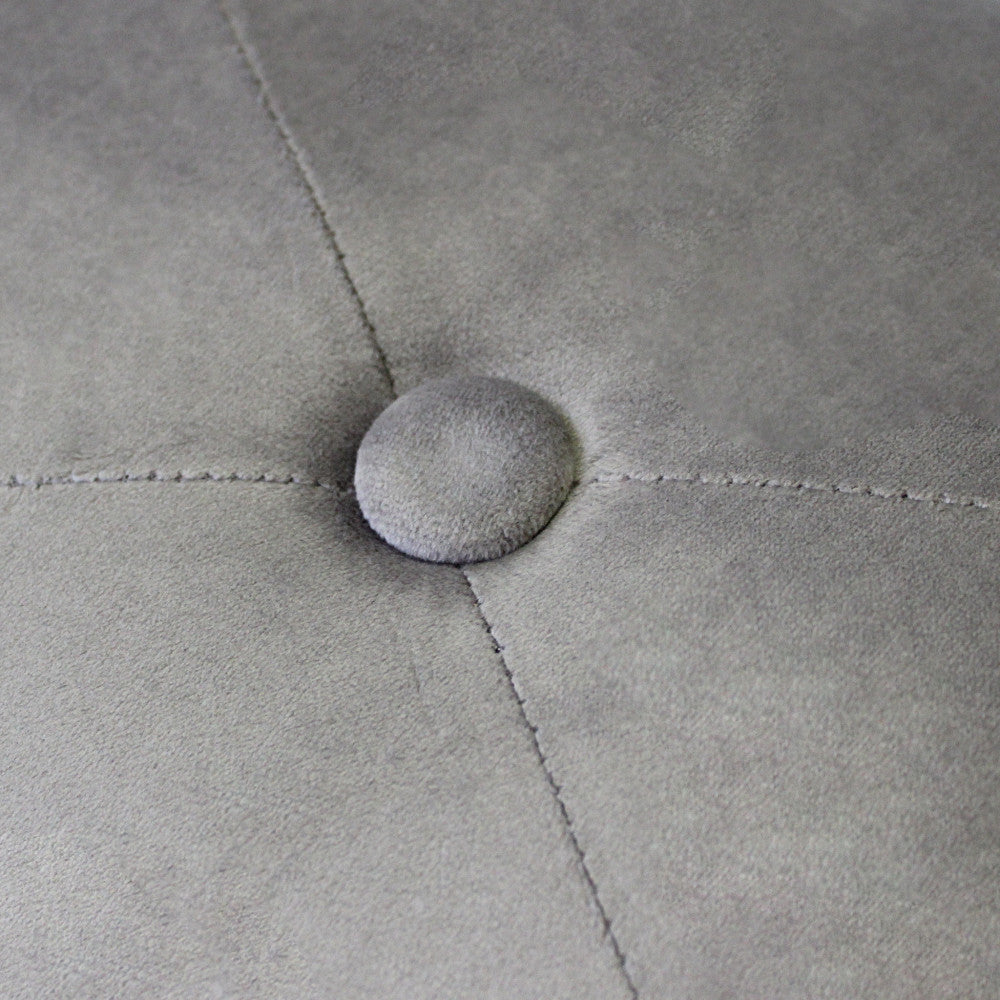 Dettaglio macro del tessuto in velluto tortora e di un singolo bottone rivestito, che evidenzia le cuciture sartoriali e la texture morbida.