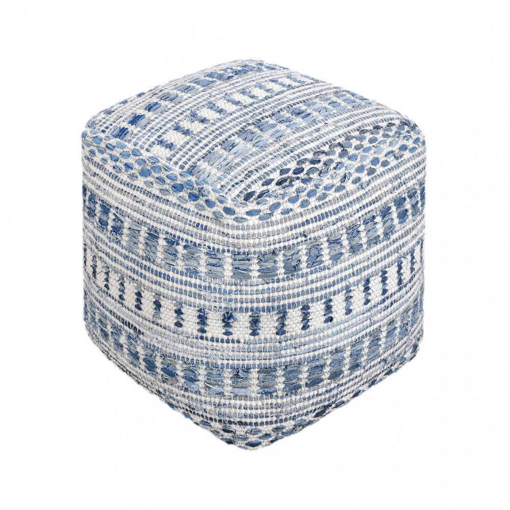 Vista isolata del pouf Sébastien 40x40 cm su sfondo bianco, che evidenzia il pattern geometrico e la lavorazione artigianale dei filati blu, azzurri e bianchi.