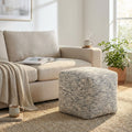Pouf Samuel in cotone blu melange e bianco, posizionato su un tappeto in juta accanto a un divano beige in un luminoso soggiorno moderno.