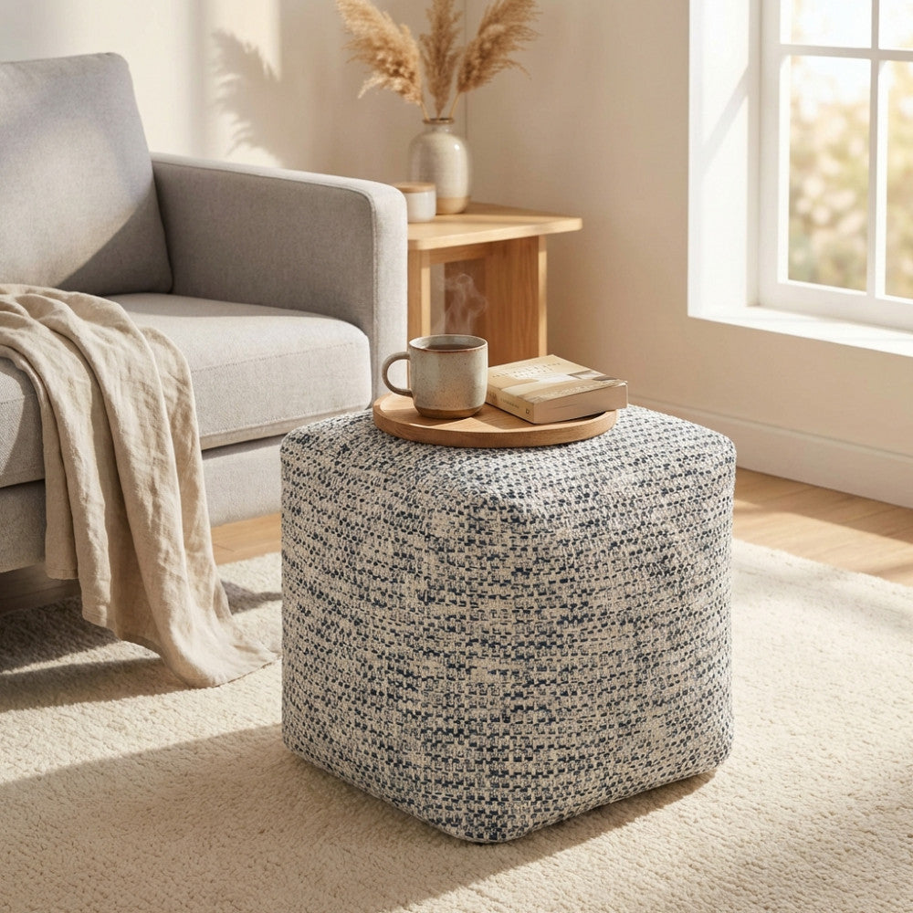 Dettaglio del Pouf Samuel utilizzato come tavolino d'appoggio con un vassoio in legno, una tazza e un libro, in un ambiente living rilassante.