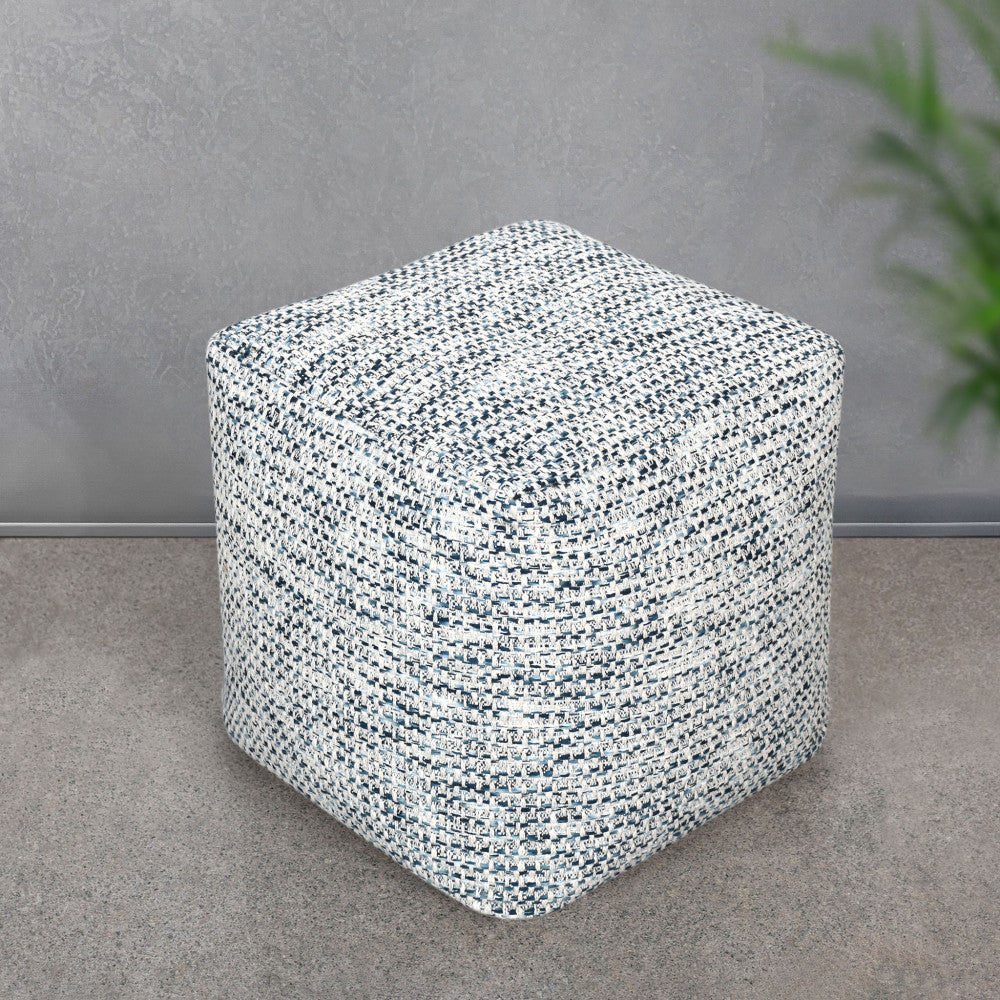 Pouf Samuel in cotone posizionato su un pavimento in pietra grigia, mostrando la sua versatilità in un contesto architettonico minimalista.