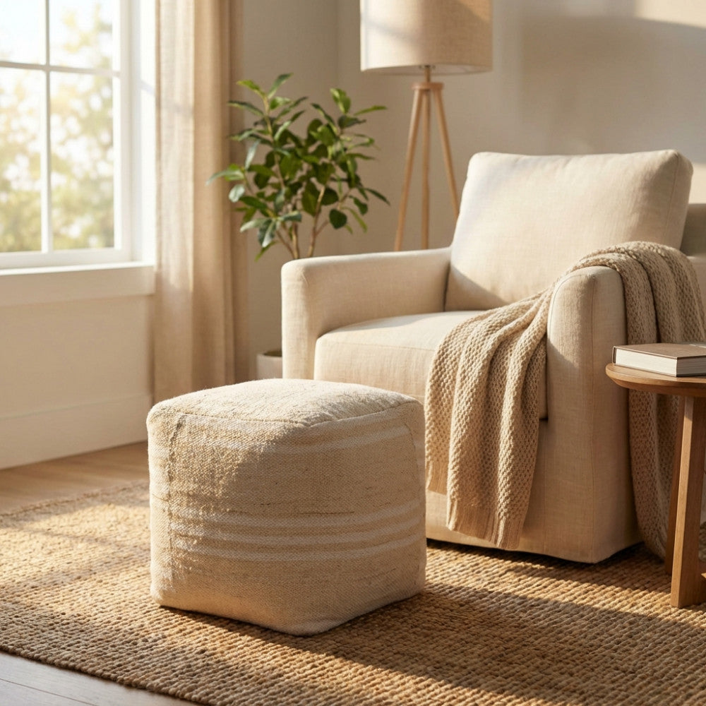 Dettaglio del pouf Théodore utilizzato come poggiapiedi vicino a una seduta con coperta in maglia.