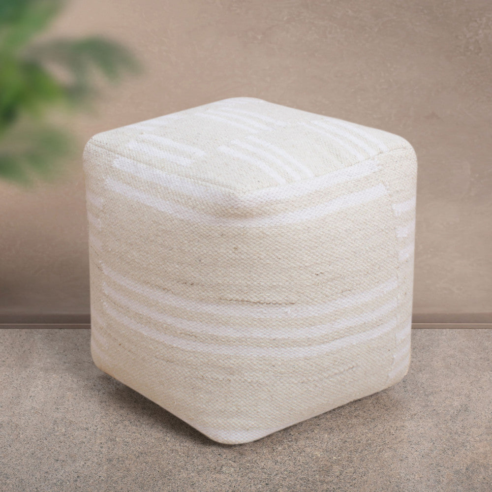 Pouf Théodore in lana bianca ecrù posizionato su un pavimento in pietra naturale.
