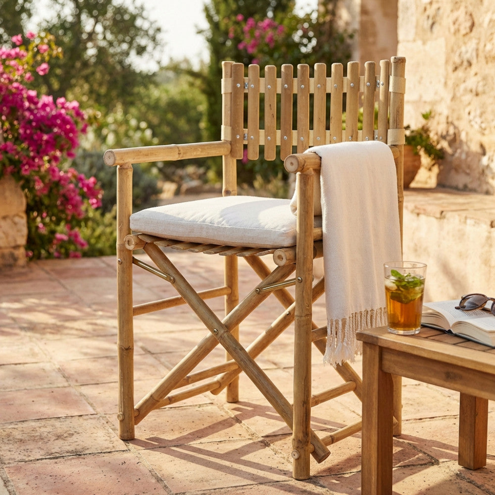 Sedia da regista Mimosa in legno con cuscino bianco e plaid su patio soleggiato.