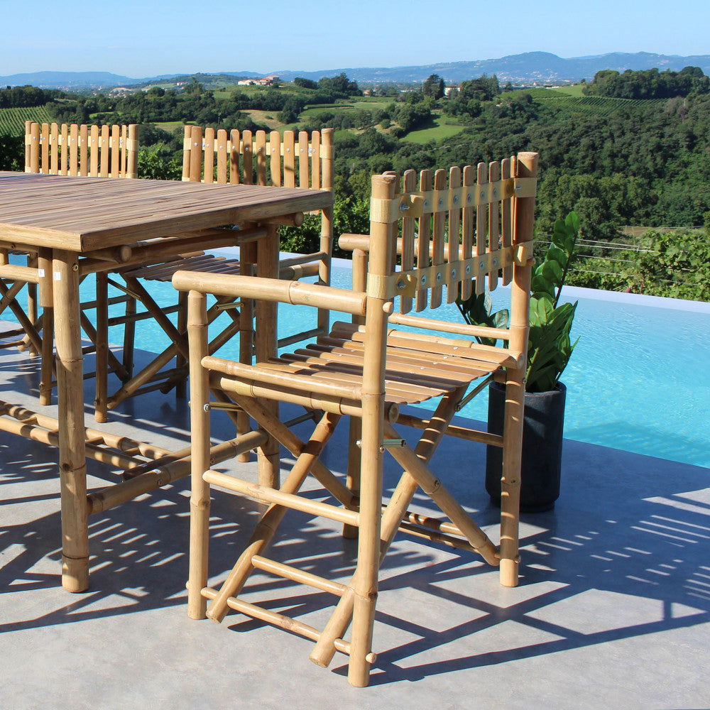 Set di sedie da regista Mimosa attorno a un tavolo in legno a bordo piscina.