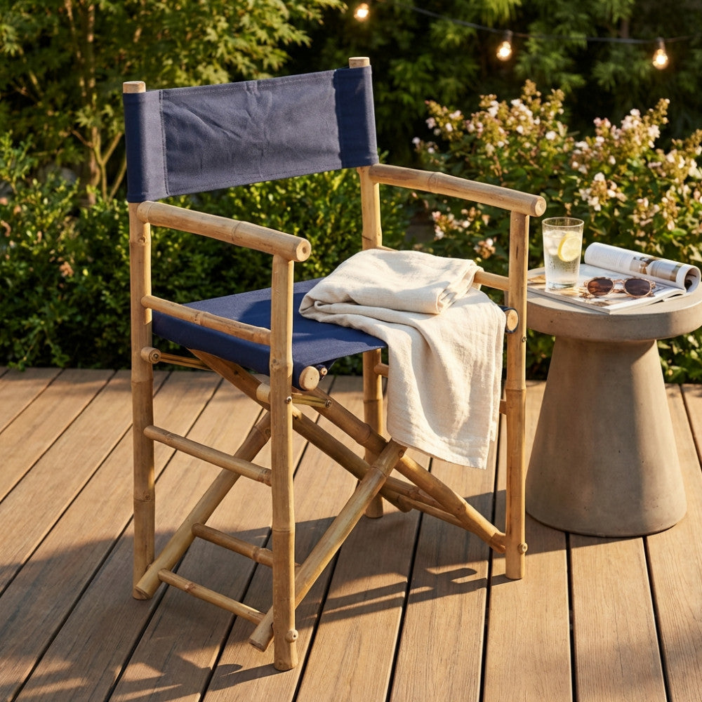 Sedia da regista in bamboo con tela blu, decorata con un telo in lino su un patio in legno.