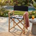 Sedia regista Mojito nera in bamboo posizionata su un patio esterno con libro e occhiali da sole sulla seduta.