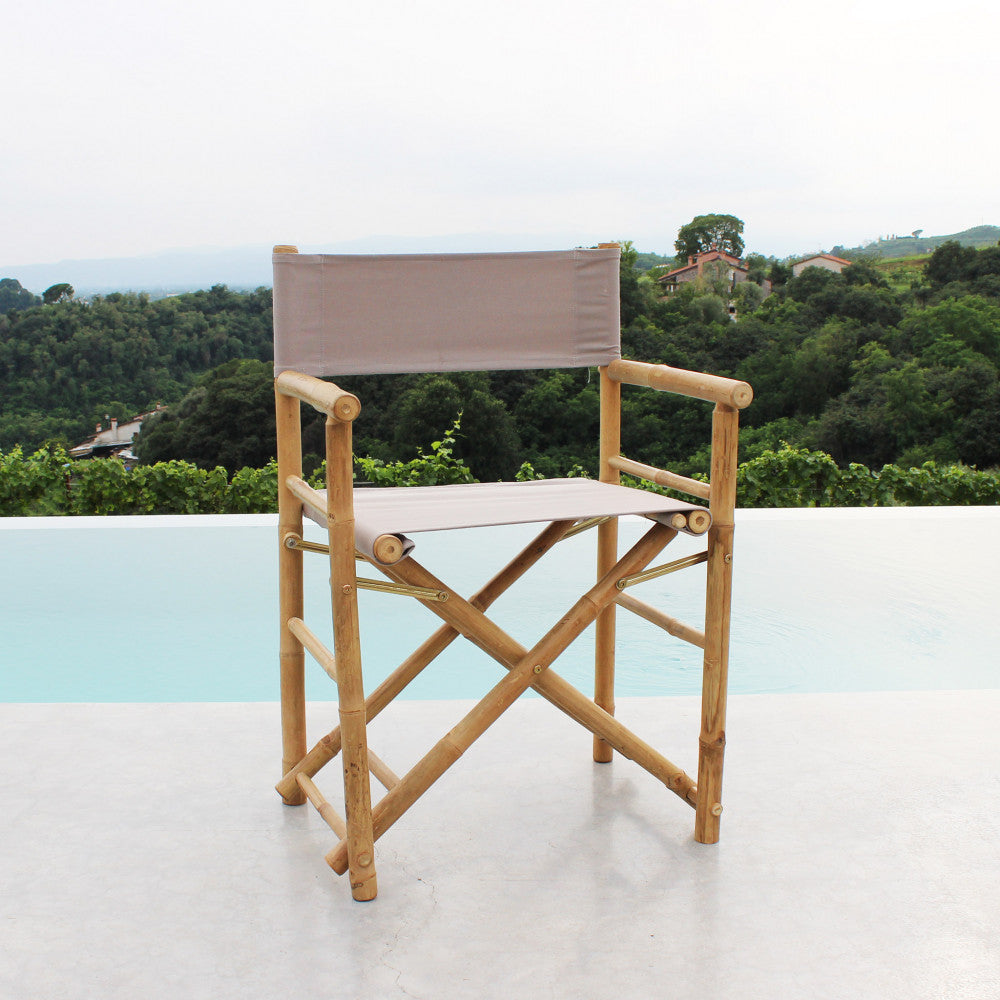 Sedia regista in legno posizionata su una terrazza in cemento con vista su colline verdi.
