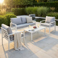 Salotto da esterno Santo Domingo in alluminio bianco ambientato in un giardino moderno al tramonto.