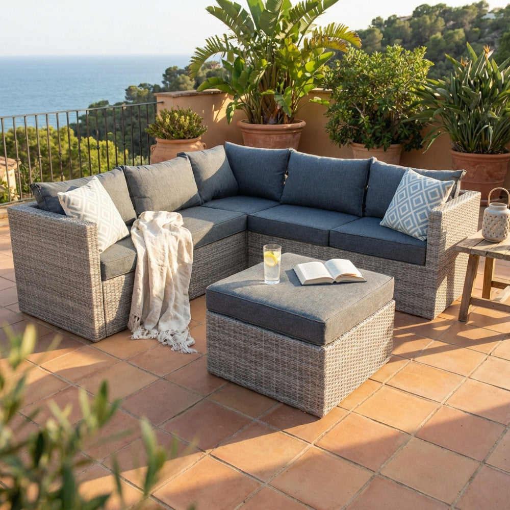 Vista frontale del salotto angolare da esterni a sei posti su una terrazza in cotto con vista mare.