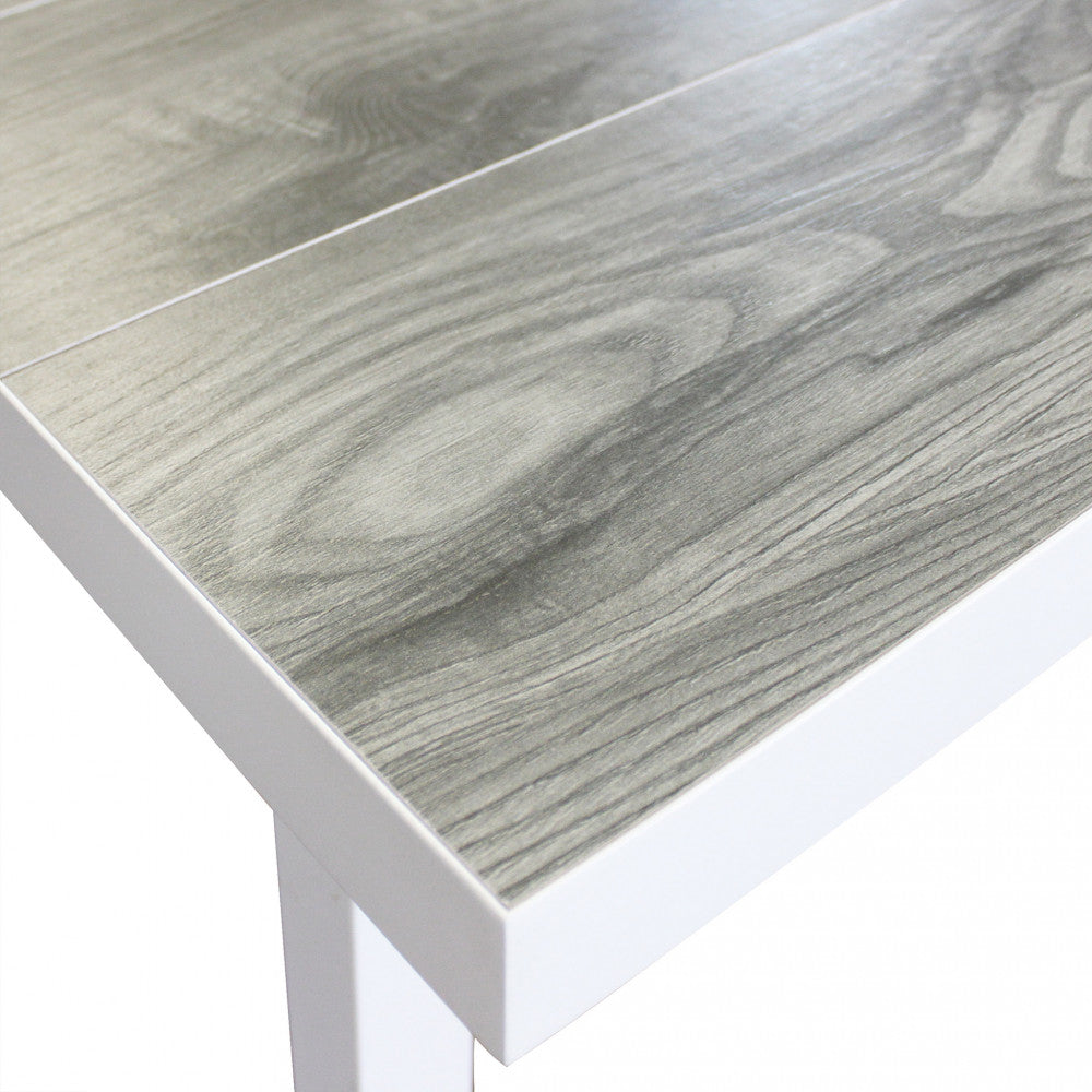 Dettaglio del piano del tavolino Boracay, che mostra la finitura effetto legno grigio incorniciata dall'alluminio bianco.