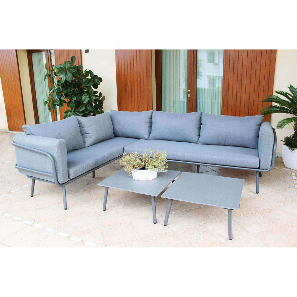 Salotto angolare Suez posizionato su un patio piastrellato, con i due tavolini centrali e piante decorative che arricchiscono l'ambiente outdoor.