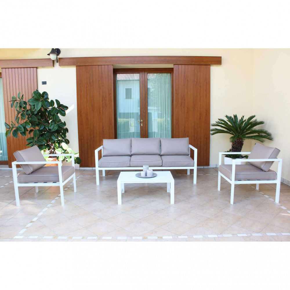 Set Salotto Avana disposto simmetricamente su un patio piastrellato, di fronte a grandi porte finestre in legno e piante ornamentali.