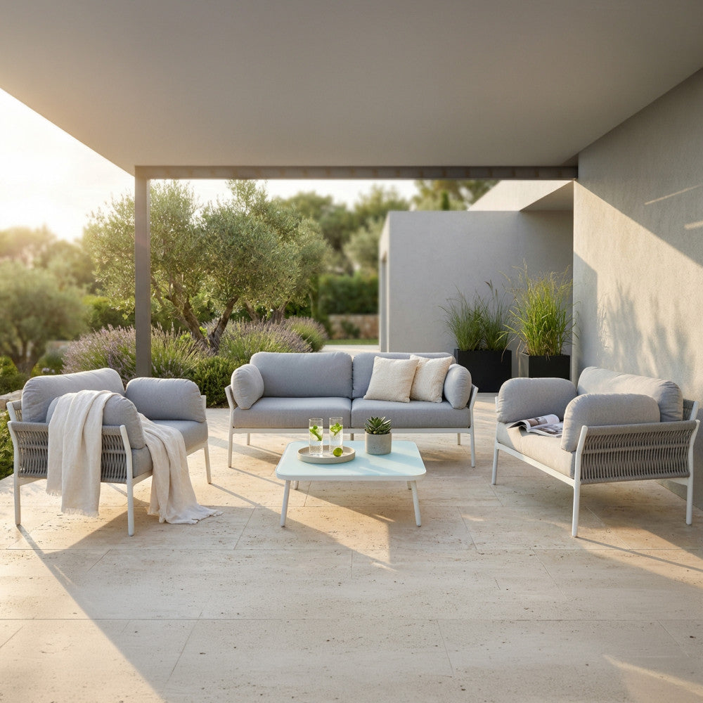 Set lounge Belém moderno posizionato in un patio elegante con pavimentazione in travertino e ulivi.