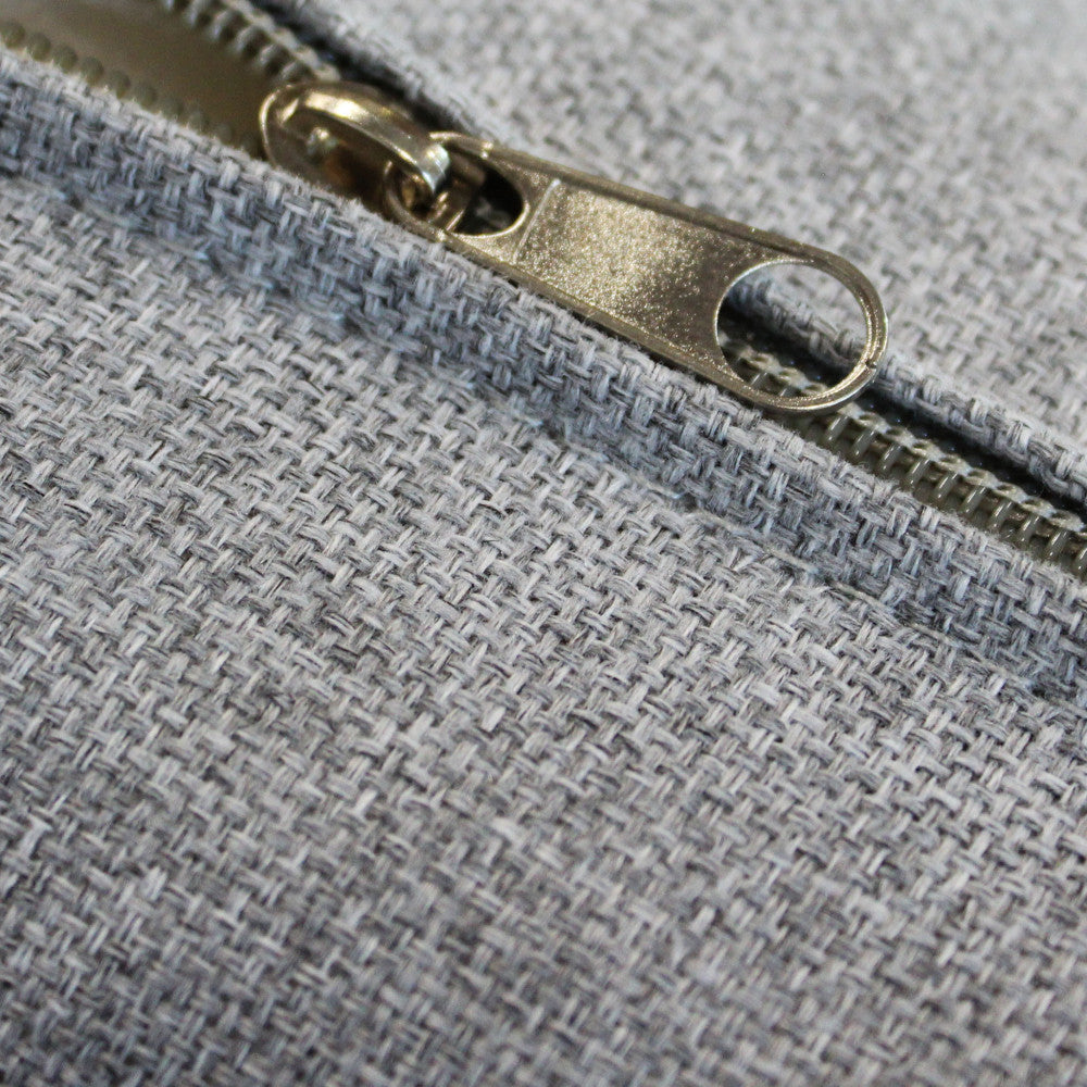 Dettaglio della cerniera metallica sul cuscino sfoderabile in misto cotone grigio chiaro del Salotto Belém.