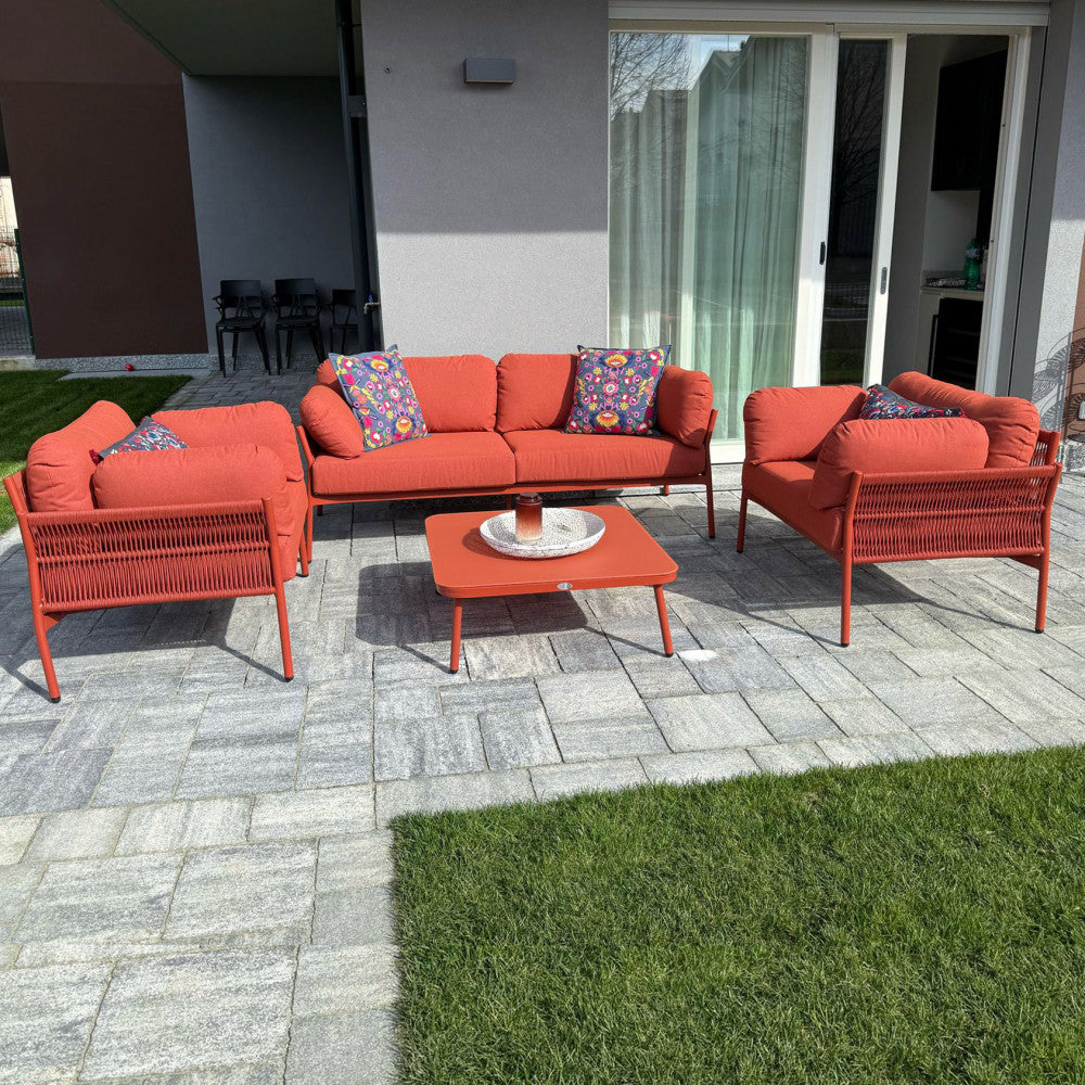Il set da esterno Belém rosso decorato con vivaci cuscini ornamentali su una terrazza contemporanea.