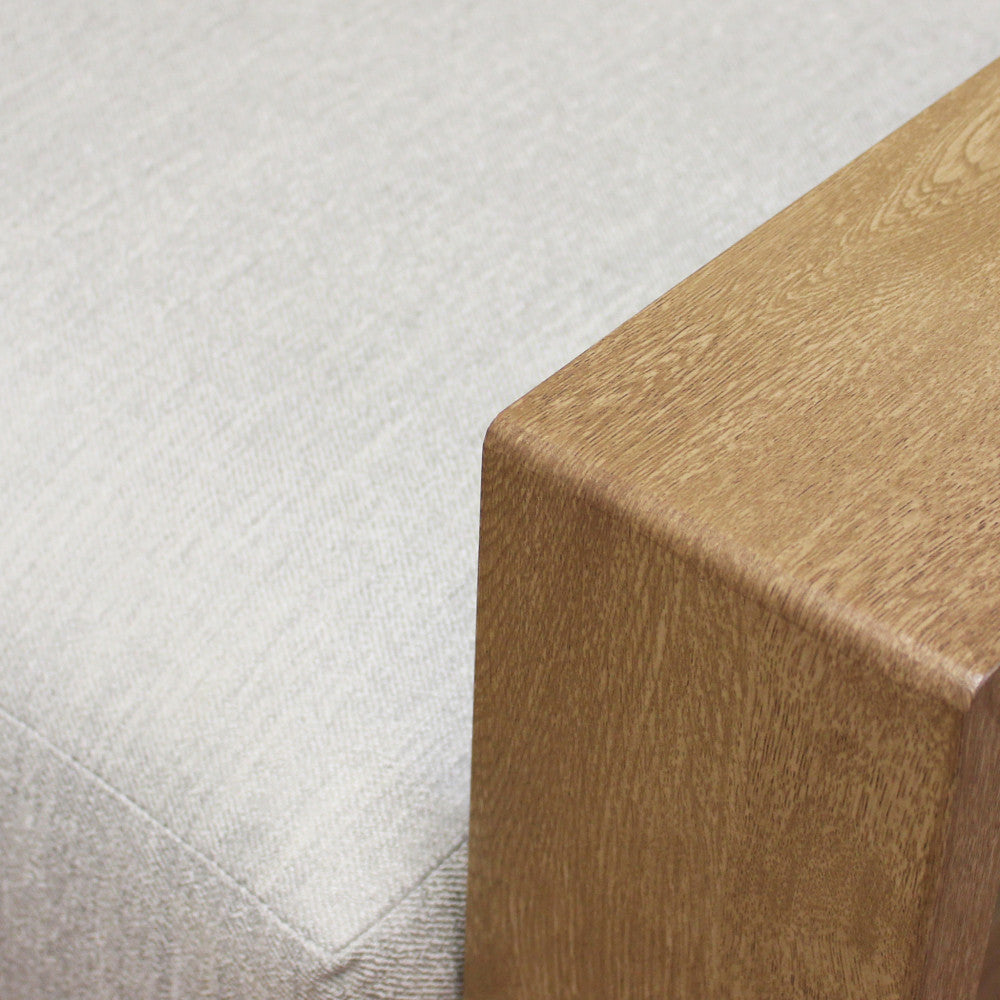 Dettaglio del bracciolo in alluminio finitura legno e del tessuto grigio chiaro.