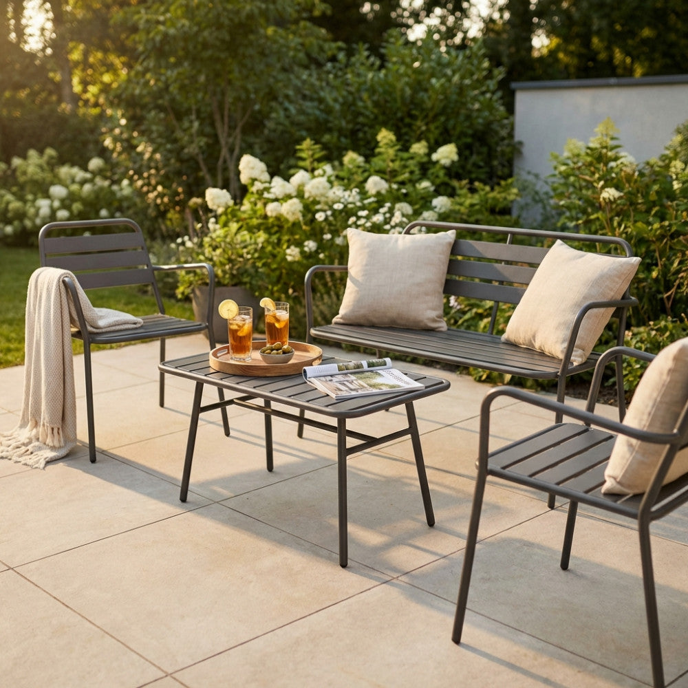Dettaglio del salotto in acciaio taupe con cuscini decorativi e bicchieri di tè freddo su una terrazza piastrellata al tramonto.
