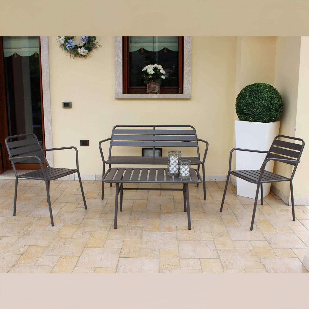 Salotto da esterno in acciaio posizionato su una veranda coperta in piastrelle, accanto a una finestra e un vaso bianco con pianta decorativa.