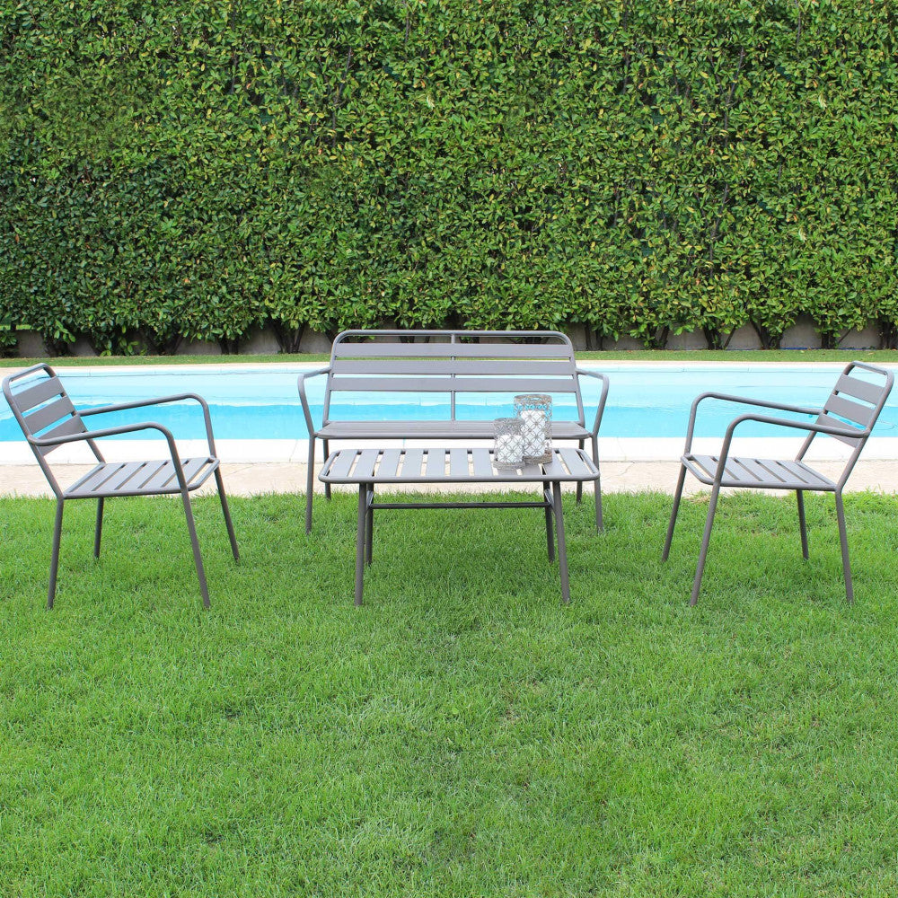 Set da giardino Bristol in acciaio taupe disposto su un prato verde curato, direttamente di fronte a una piscina azzurra con siepe sullo sfondo.
