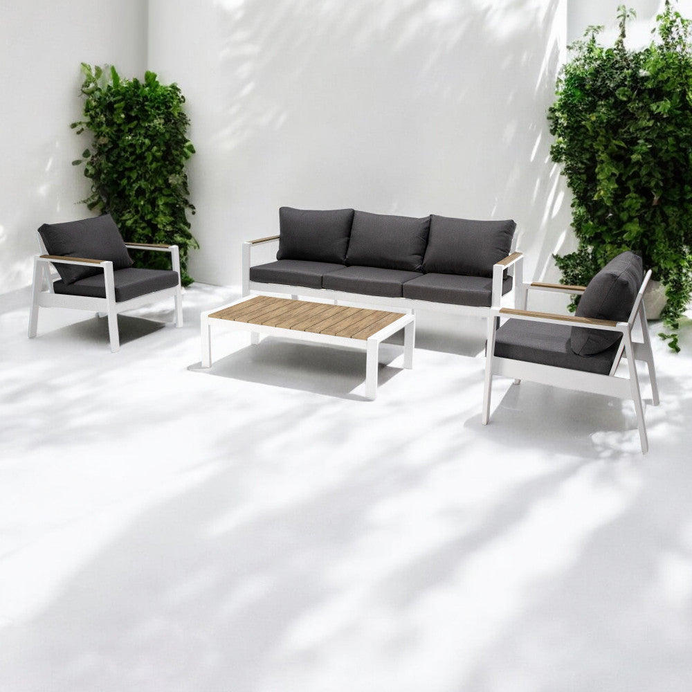 Set lounge Córdoba posizionato in un cortile minimalista bianco con rigogliose piante verdi, evidenziando il contrasto cromatico.