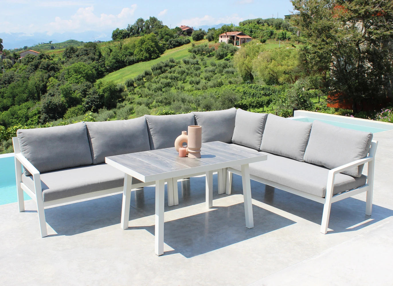 Salotto Angolare Boracay da esterno in Alluminio Verniciato Bianco con cuscini, composto da divano, poltrona e tavolino, ambientato a bordo piscina