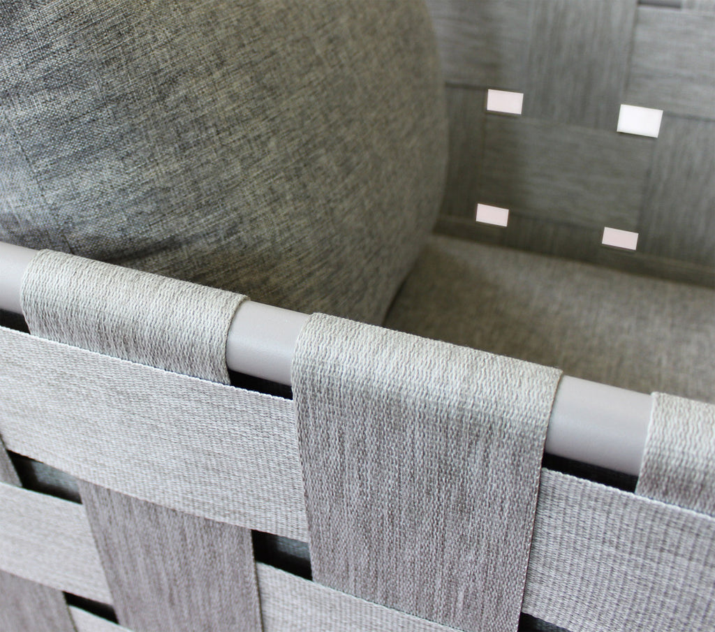 Primo piano del bracciolo in alluminio avvolto dall'elegante intreccio a nastro in tessuto grigio.