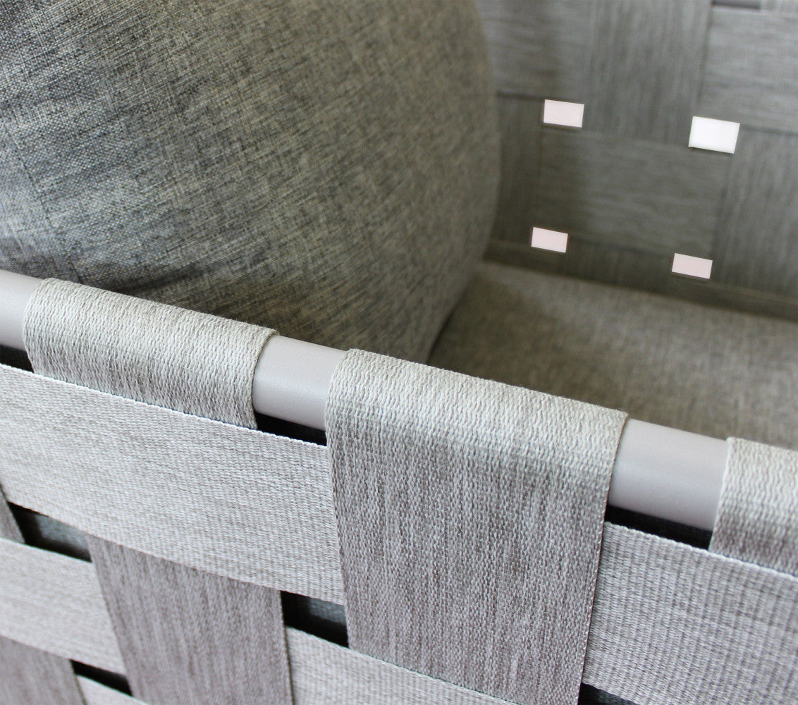 Primo piano del bracciolo in alluminio avvolto dall'elegante intreccio a nastro in tessuto grigio.
