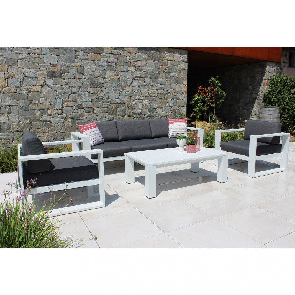 Salotto Knoxville posizionato su un patio in pietra chiara di fronte a un muro rustico in pietra.