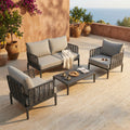 Salotto Marigot a 4 posti in HPL e PVC color antracite, ambientato su una terrazza soleggiata con vista mare.