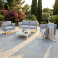 Salotto da esterno Minneapolis a 4 posti in alluminio bianco e textilene grigio, allestito su un patio in pietra naturale al tramonto.
