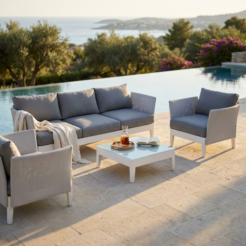 Set lounge da giardino Minneapolis con divano, due poltrone e tavolino, illuminato dalla calda luce del tramonto.