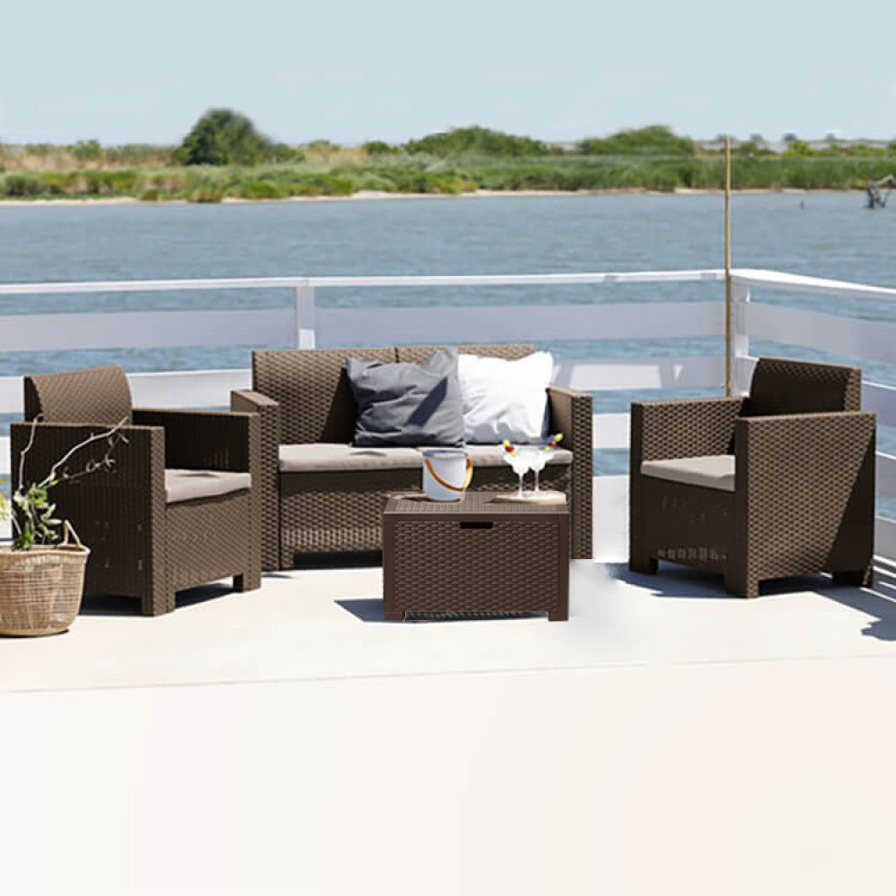Salotto Nebraska marrone allestito su una terrazza in legno bianco con vista panoramica su un lago e vegetazione naturale.